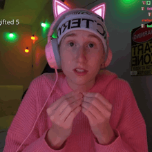 a girl wearing a pink sweater and headphones has a sign that says gifted 5