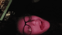 a person wearing glasses has their mouth open in a dark room