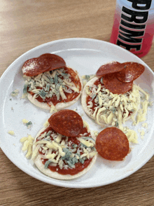 a white plate topped with four pizzas next to a bottle that says prime