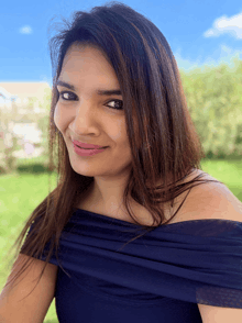 a woman in a blue off the shoulder top is smiling