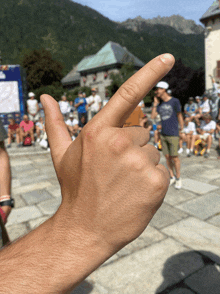 a man 's hand is making a thumbs up sign in front of a crowd