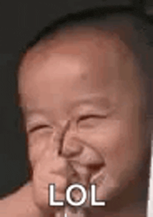 a baby is making a funny face and laughing with the word lol on it .