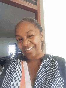 a woman wearing a black and white polka dot shirt smiles for the camera