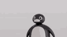 a black and white penguin toy is standing on a white background .