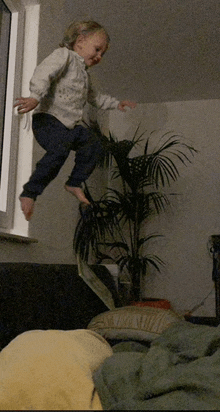 a little girl is jumping in the air in front of a palm tree