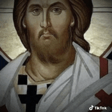 a close up of a painting of jesus with a cross on his shirt