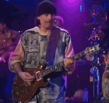 a man playing a guitar with a band behind him that says ' santana ' on it