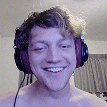 a shirtless man wearing headphones is smiling