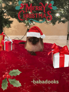 a cat wearing a santa hat sits on a table with gifts under a christmas tree