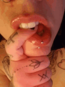 a close up of a woman 's mouth with a tattoo of a flower on her finger