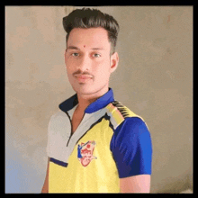 a young man is wearing a yellow and blue shirt with a logo on it .