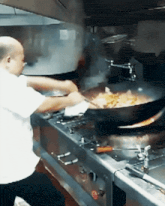 a man in a white shirt is cooking food on a stove top