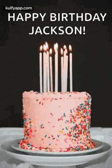 a birthday cake with candles and sprinkles on it is on a plate on a table .