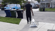 a man is walking down a sidewalk carrying a bag that says 2025 on it