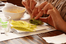 a person 's hands are reaching for a piece of food on a plate that has a green leaf on it