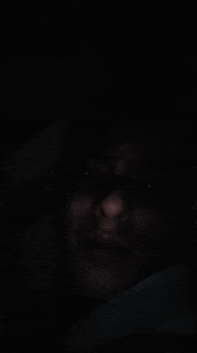 a close up of a man 's face in the dark with his eyes visible