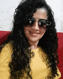 a woman wearing sunglasses and a yellow shirt is smiling