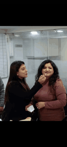 a woman applying lipstick to another woman 's lips