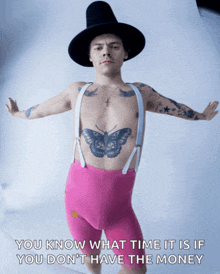 a man with a butterfly tattoo on his chest is wearing suspenders and a hat