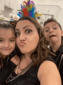 a woman wearing a headband with feathers on it poses for a photo with two children