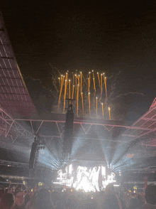 a crowd watching fireworks in a stadium with a sign that says exit on it