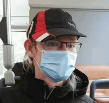 a man wearing a baseball cap and glasses is wearing a face mask .