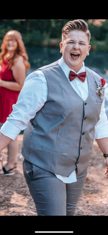 a man in a suit and bow tie is laughing with a woman in a red dress behind him