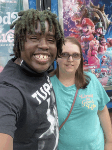 a man wearing a black t-shirt that says turn 7 poses with a woman wearing a living good life t-shirt