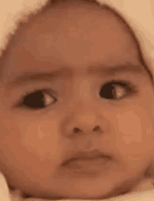 a close up of a baby 's face with a sad look on it .