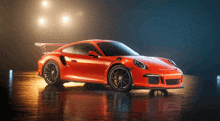 a bright orange sports car is parked on a wet road