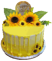 a yellow birthday cake with sunflowers on top and a happy birthday sign