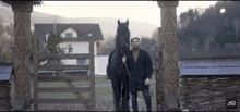 a man stands next to a black horse with the letter mr on the bottom