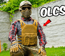 a man wearing a helmet and goggles is kneeling down in front of a brick wall with the word olcs visible