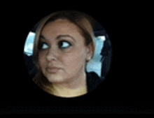 a close up of a woman 's face in a circle on a black background