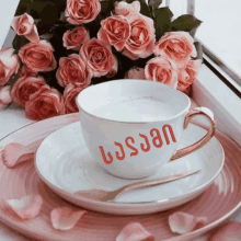 a cup of coffee with the name jason written on it sits on a plate next to a bouquet of pink roses