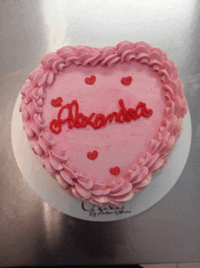 a heart shaped cake with the name alexandra written in red