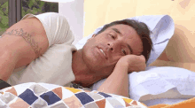 a man is laying in bed with his head on his hand .