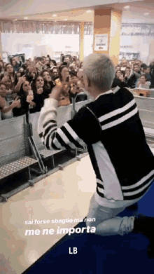 a man in a black and white striped shirt is kneeling down in front of a crowd with the letters lb below him