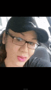 a woman wearing glasses and a black hat is sitting in a car