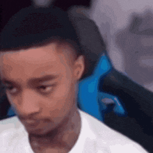a man in a white shirt is sitting in a blue gaming chair .