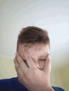 a young boy covering his face with his hands