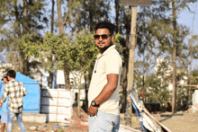 a man wearing sunglasses and a watch stands in a park