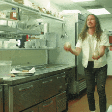 a man in a white shirt is standing in a kitchen with a bottle of fire extinguisher on the shelf