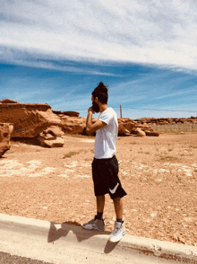 a man in a white shirt and black shorts is standing on the side of the road