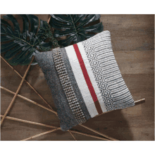 a grey and white pillow with a red stripe on the side