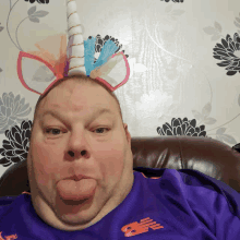 a man wearing a unicorn headband is sticking out his tongue