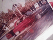 a picture of a red car parked on the side of a road