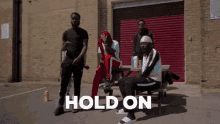 a group of men are standing and sitting at a picnic table with the word hold on written on the ground