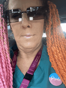 a woman with pink braids wearing sunglasses and a pride pin