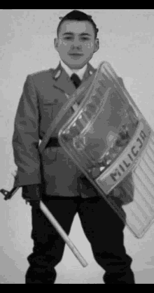 a black and white photo of a police officer holding a shield and baton